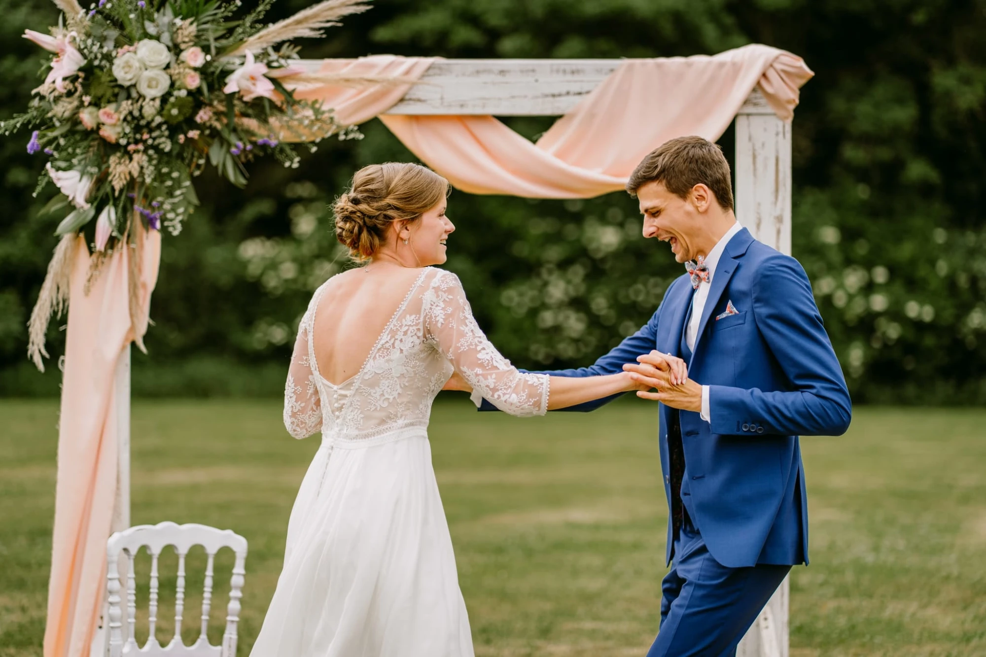 Mariée et marié dansant sous une arche fleurie lors de leur mariage photographe-lille