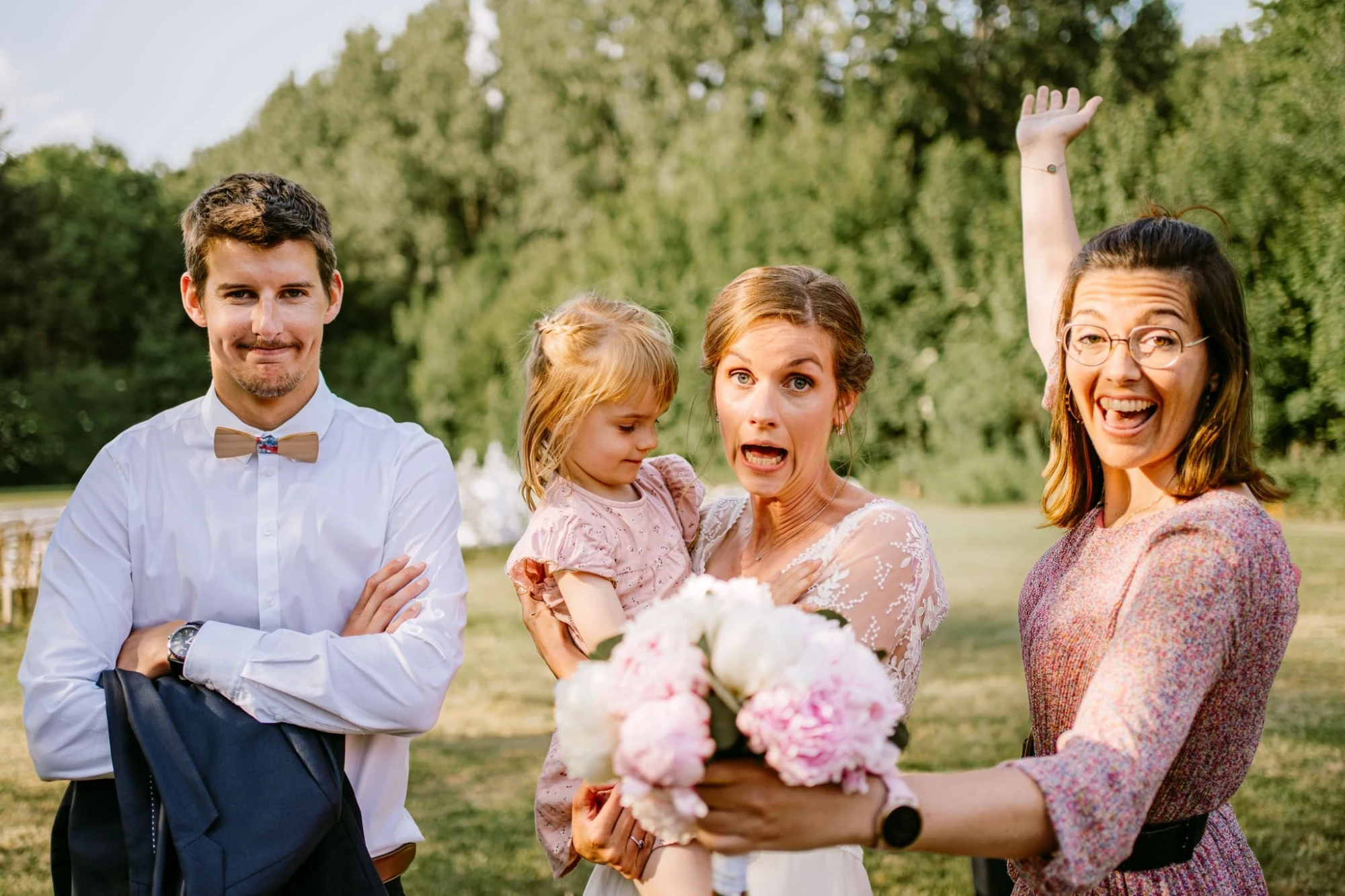 Groupe joyeux à un mariage : marié, mariée avec enfant, invitée levant le bras. photographe-lille