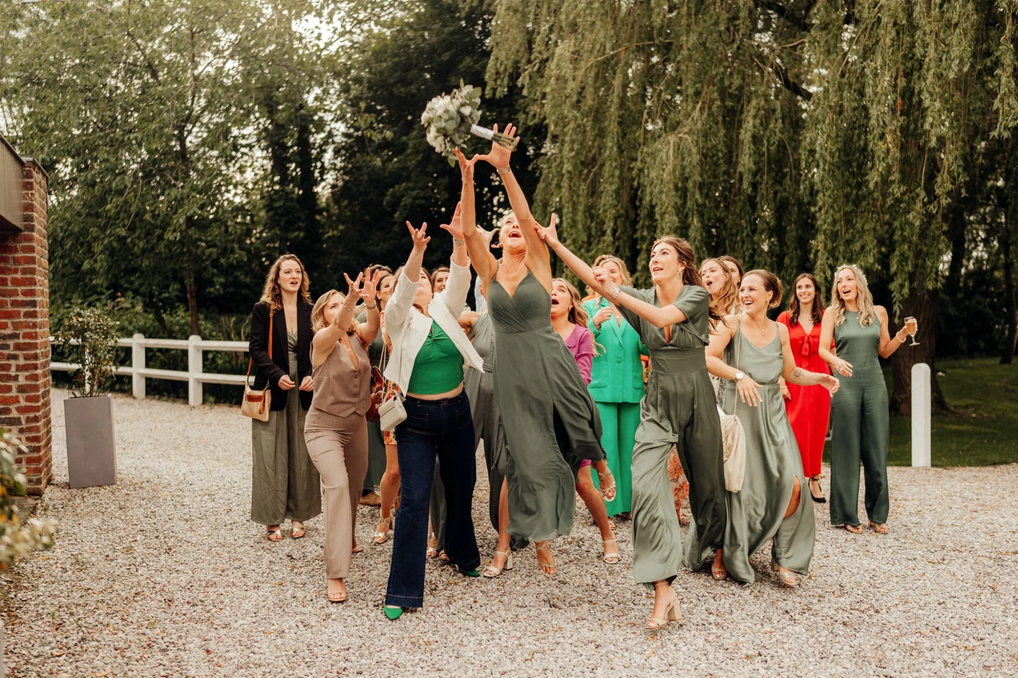 Un groupe de femmes attrapent un bouquet de fleurs lors d'un mariage, à l'extérieur. photographe-lille