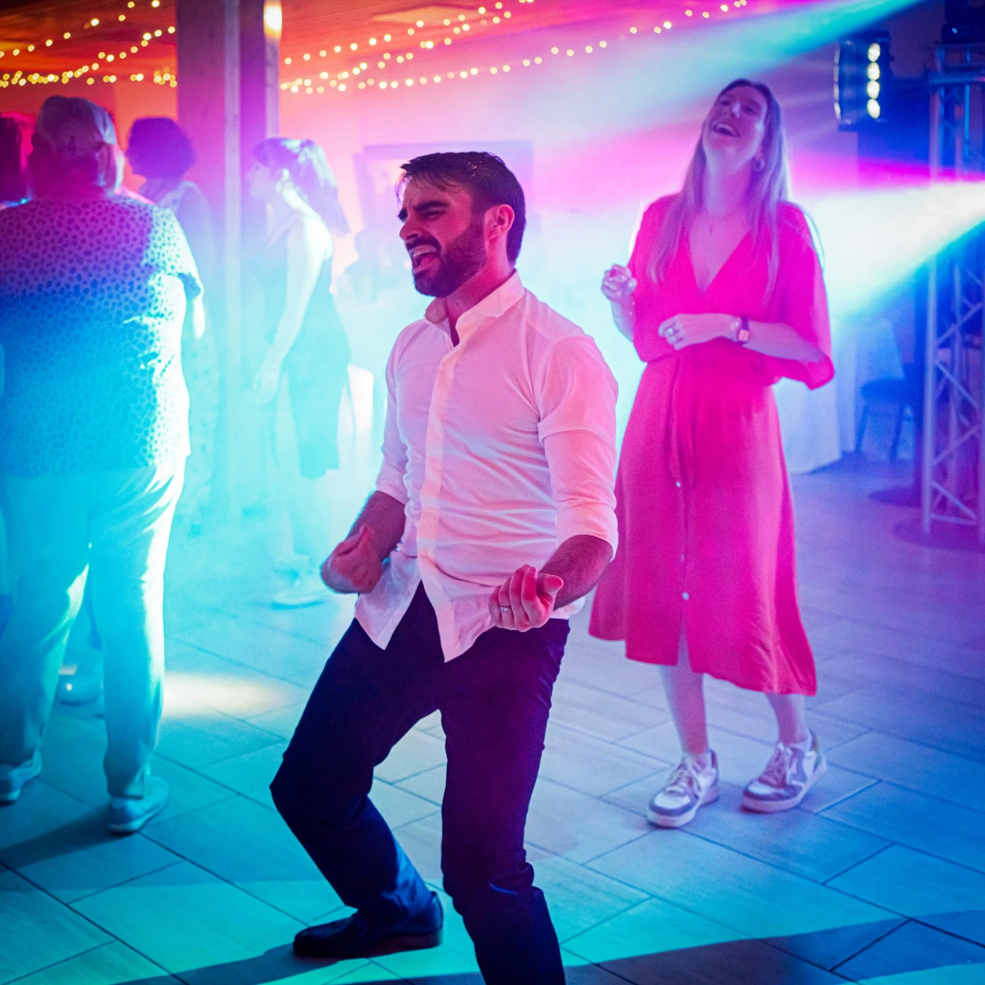 Homme dansant à une fête avec des amis, éclairage coloré et ambiance festive. photographe-lille