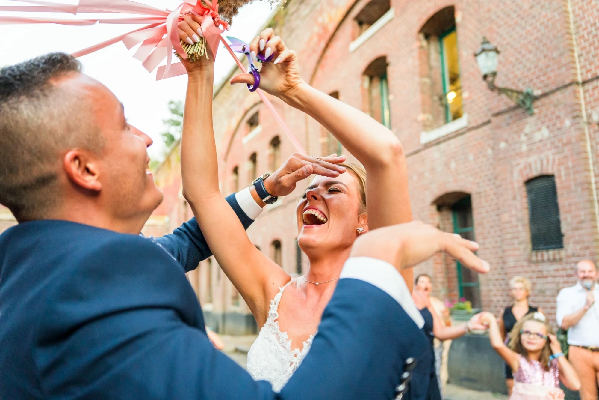 Les mariés rient en coupant le gâteau de mariage en plein air photographe-lille