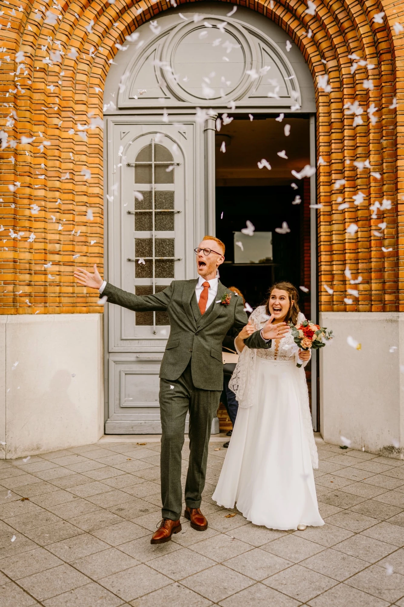 Jeunes mariés rayonnants sortant d'une mairie sous une pluie de confettis. photographe-lille