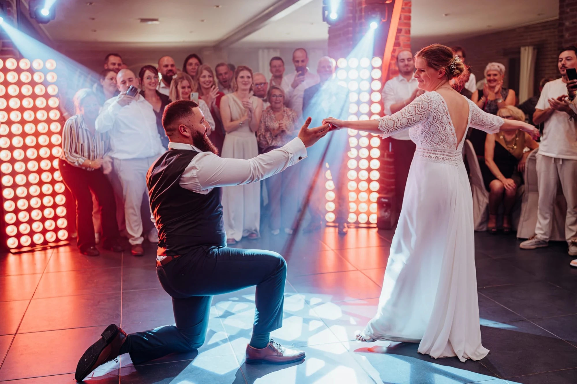 Les mariés dansent sous des lumières colorées lors d'une réception de mariage photographe-lille
