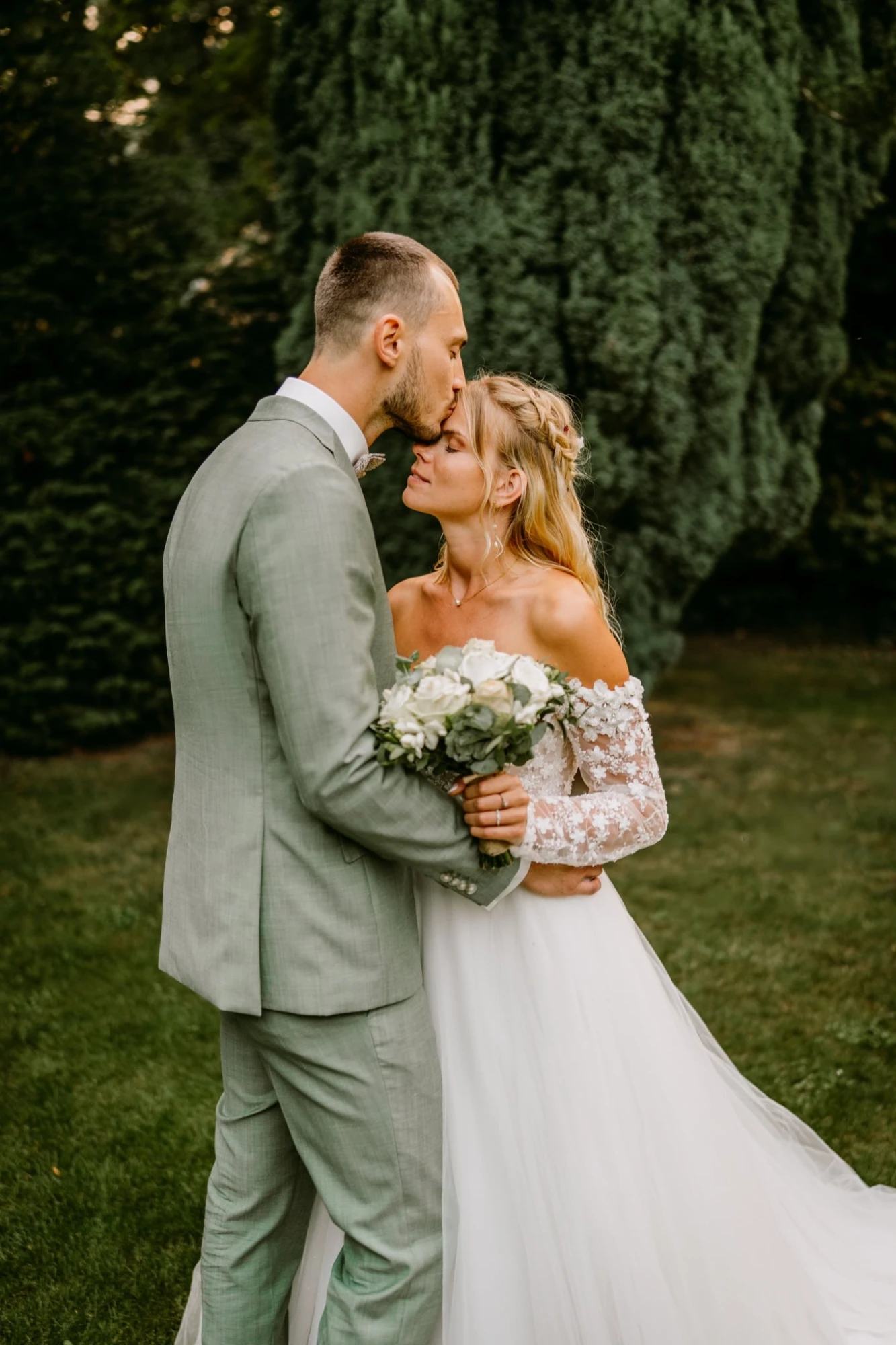 Mariés s'embrassant sur le front, robe blanche et costume vert photographe-lille