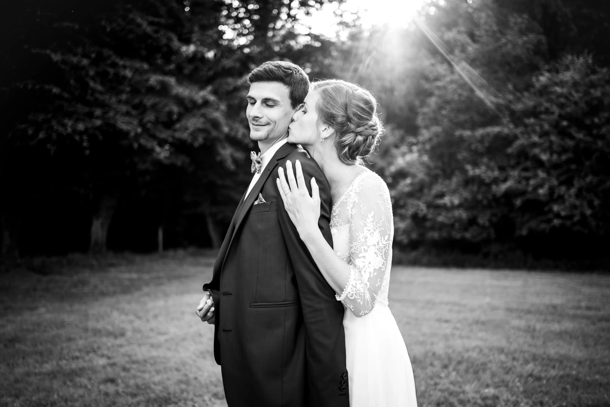 Mariée embrassant le marié dans un cadre verdoyant ensoleillé. Couple de mariage romantique. photographe-lille