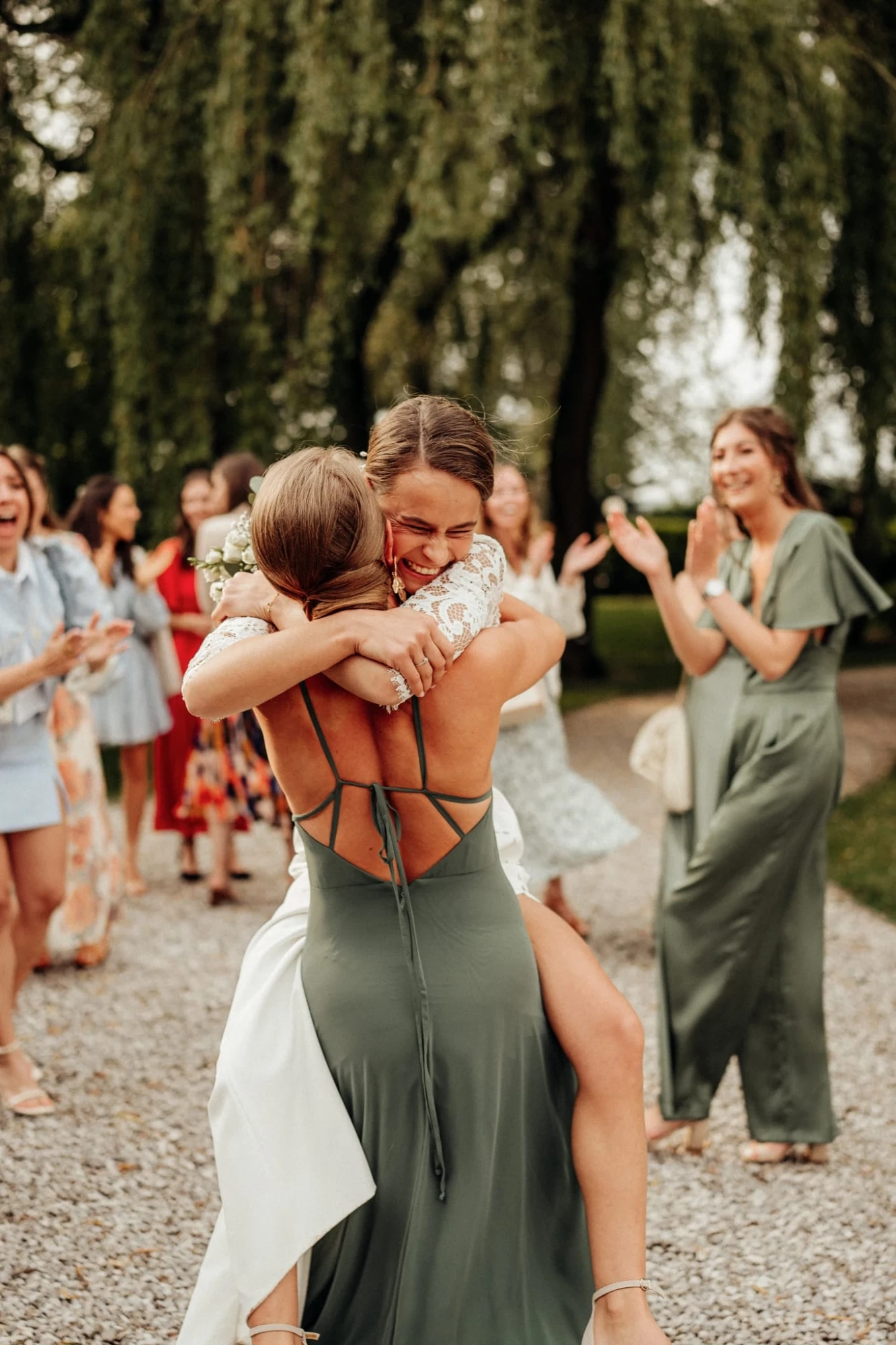 Deux femmes s'enlacent lors d'un mariage en plein air, entourées d'invités enthousiastes. photographe-lille