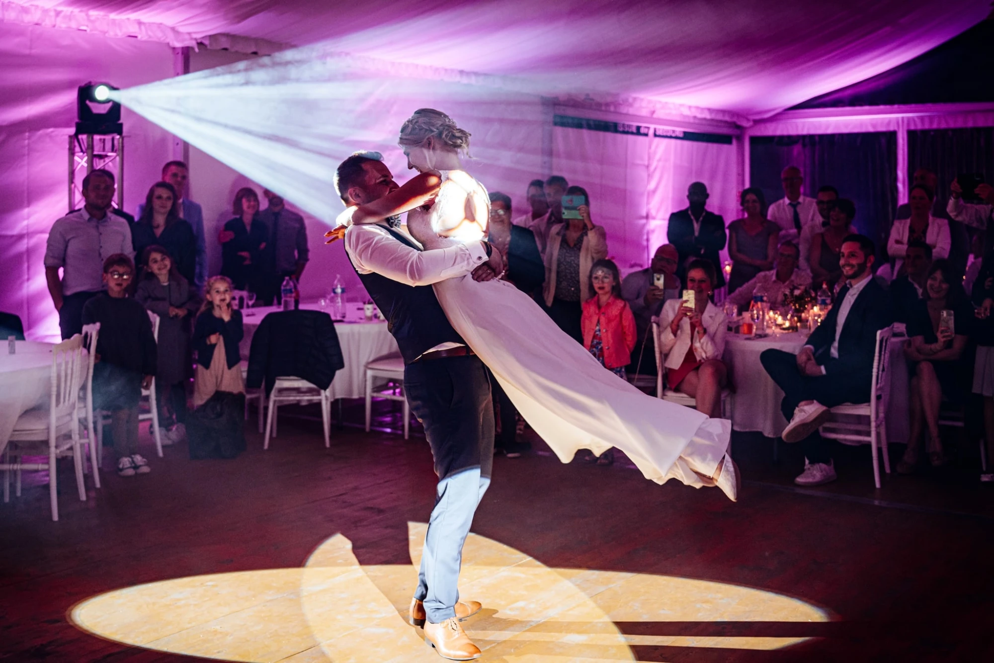 Marié portant la mariée lors de la première danse sous un projecteur violet. photographe-lille