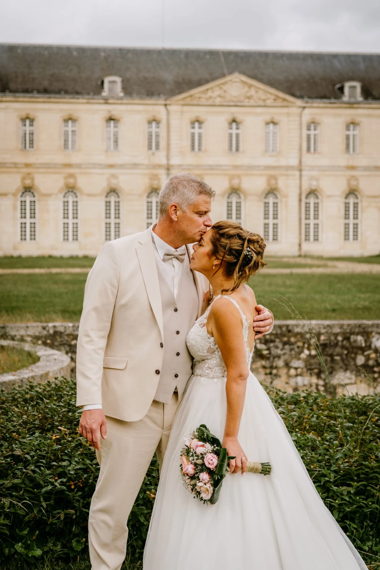 Marié embrassant la mariée devant un château. Couple de mariage romantique. photographe-lille