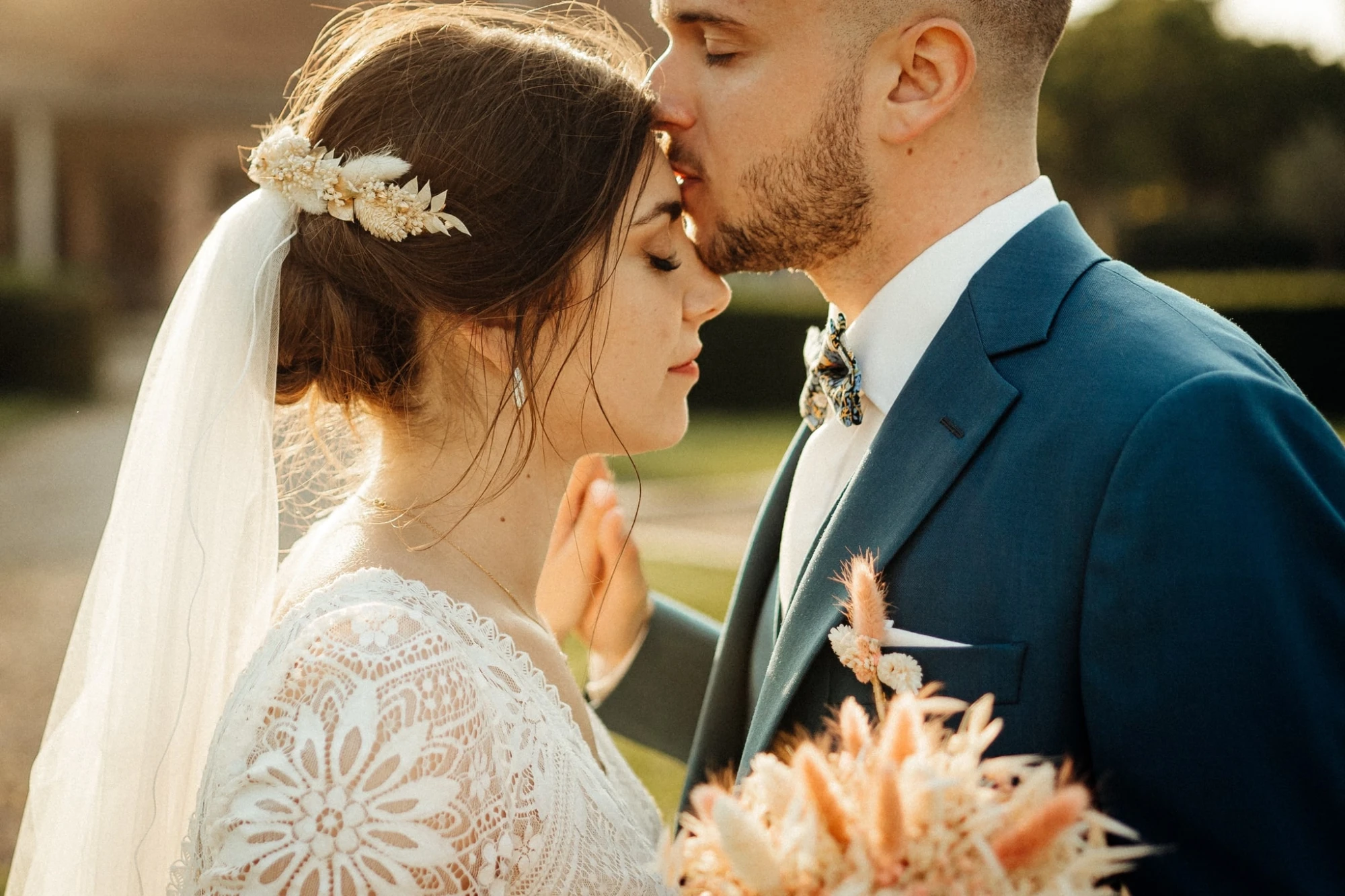 Le marié embrasse le front de la mariée lors d'une cérémonie de mariage en plein air photographe-lille
