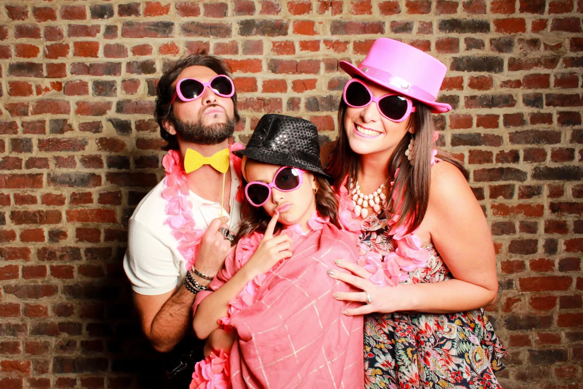 Famille souriante portant des accessoires de fête devant un mur de briques. photographe-lille