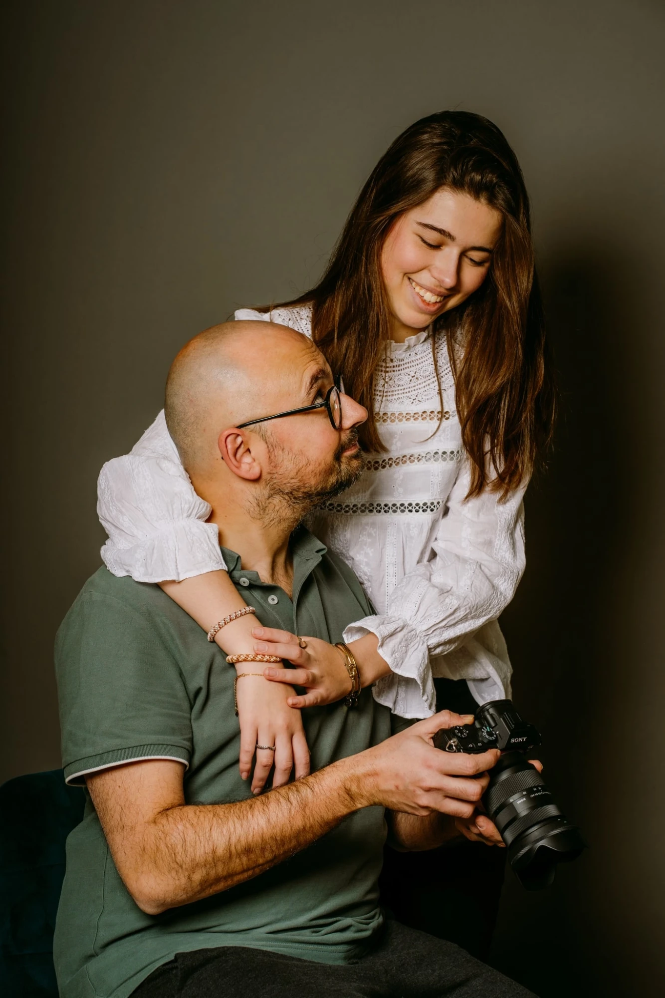 Photographe à Lille : Père et fille regardant un appareil photo Sony avec affection. photographe-lille
