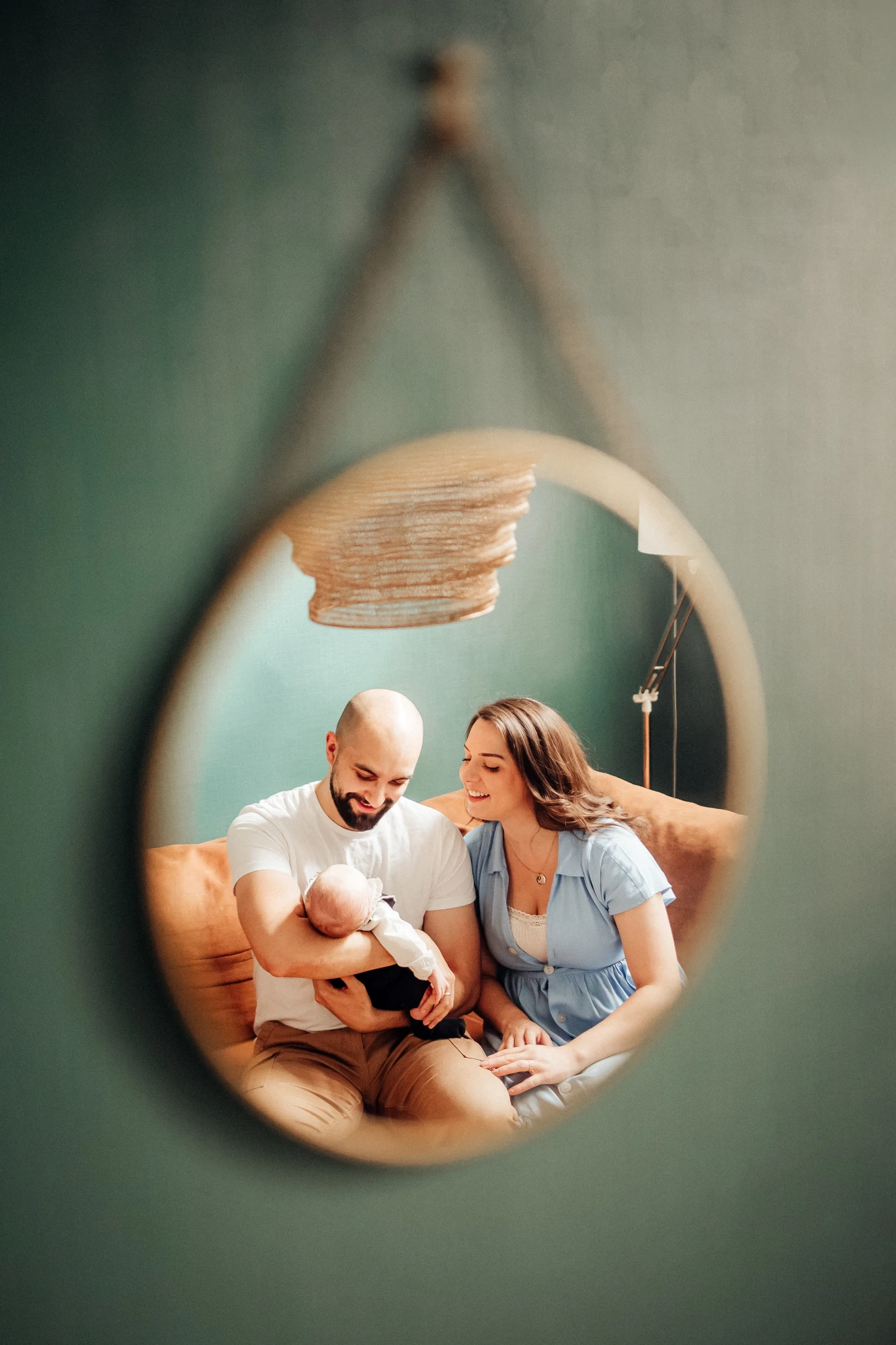 Reflet dans un miroir d'une famille avec un nouveau-né sur un canapé. photographe-lille