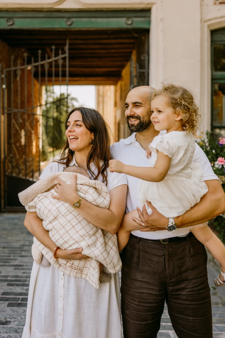 Famille heureuse avec bébé et enfant en bas âge devant un bâtiment en brique. photographe-lille
