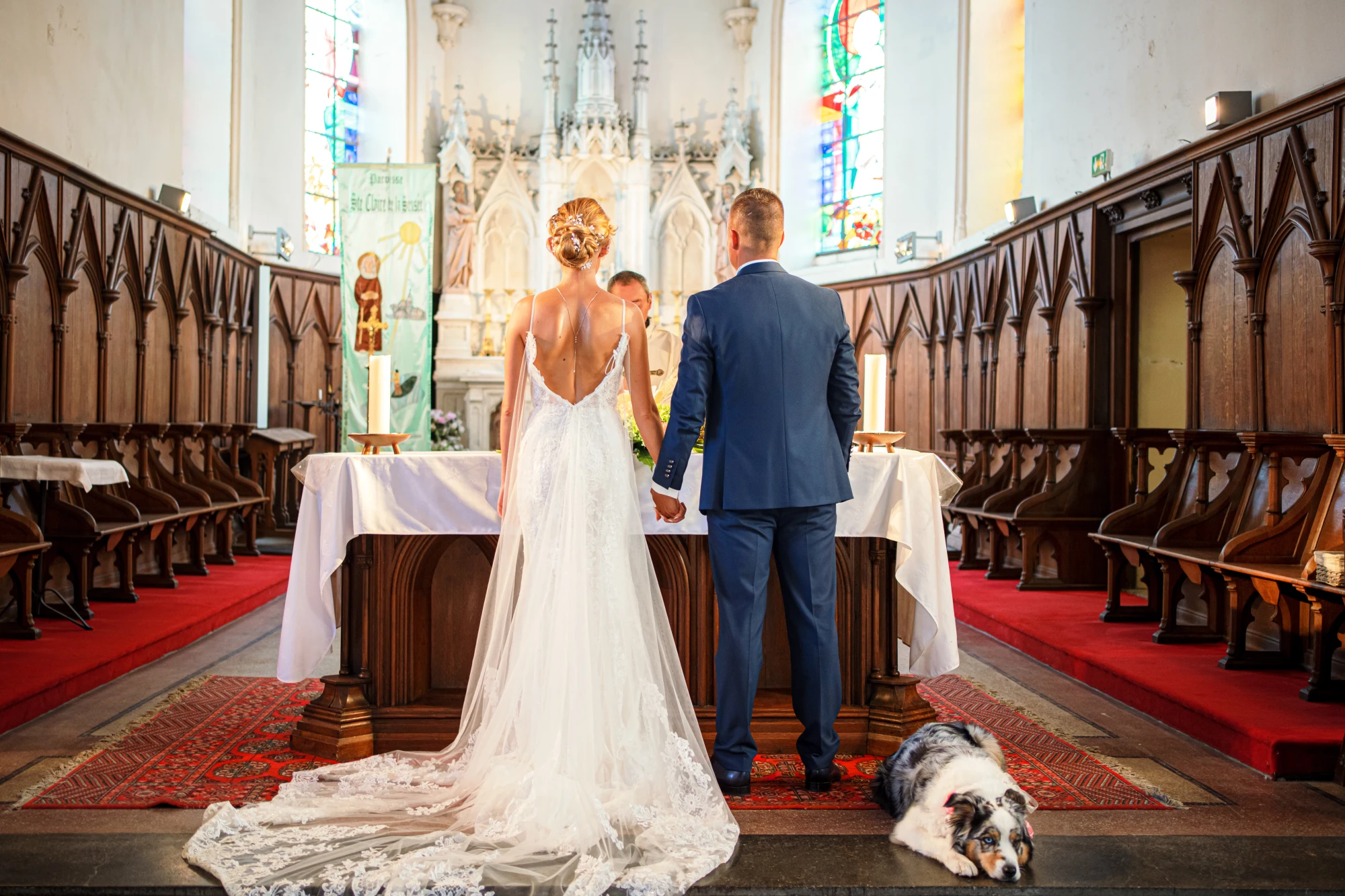Mariage : Couple devant l'autel dans une église avec un chien couché. photographe-lille